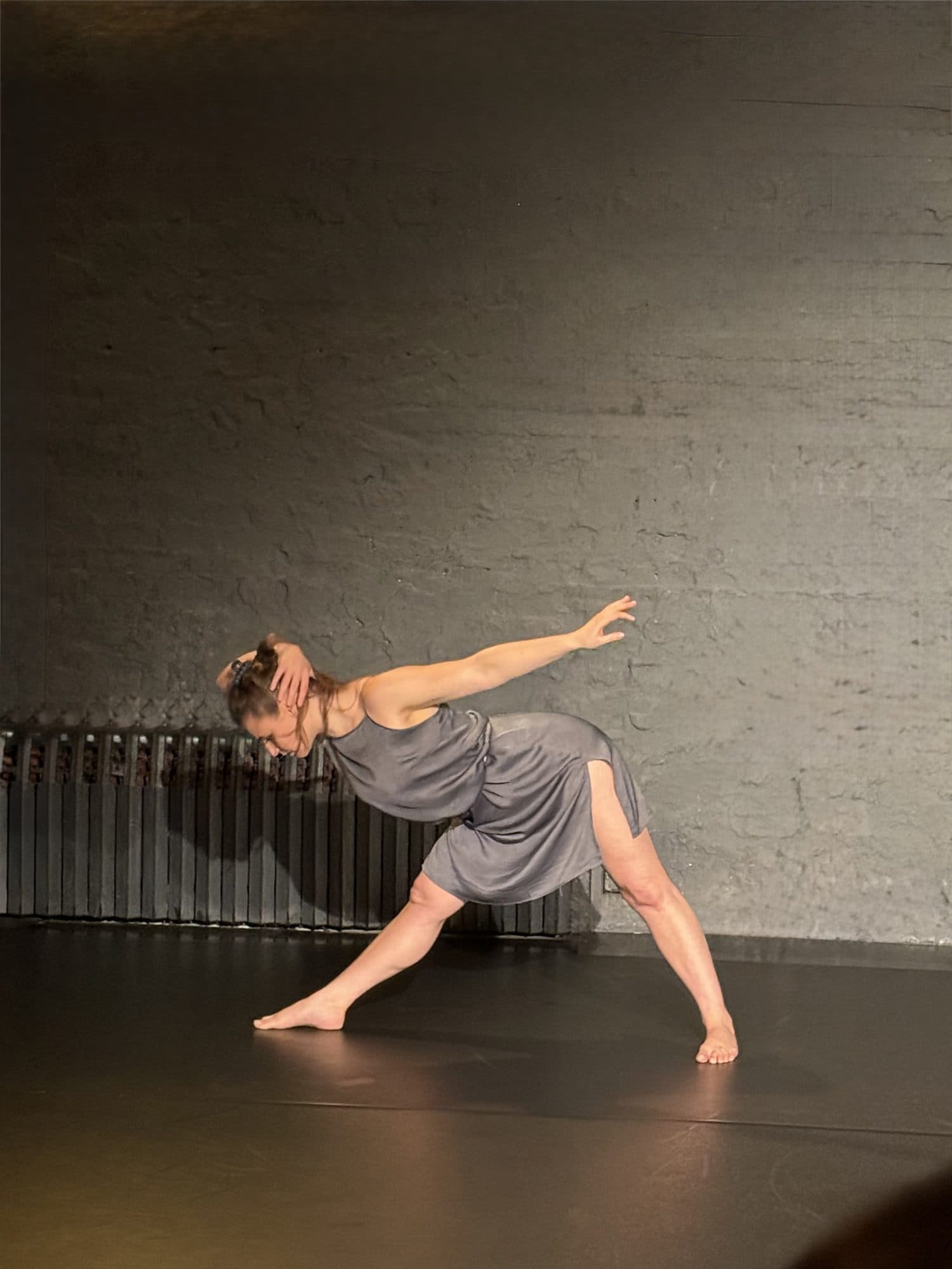 Laura reaching sideways against a brick wall