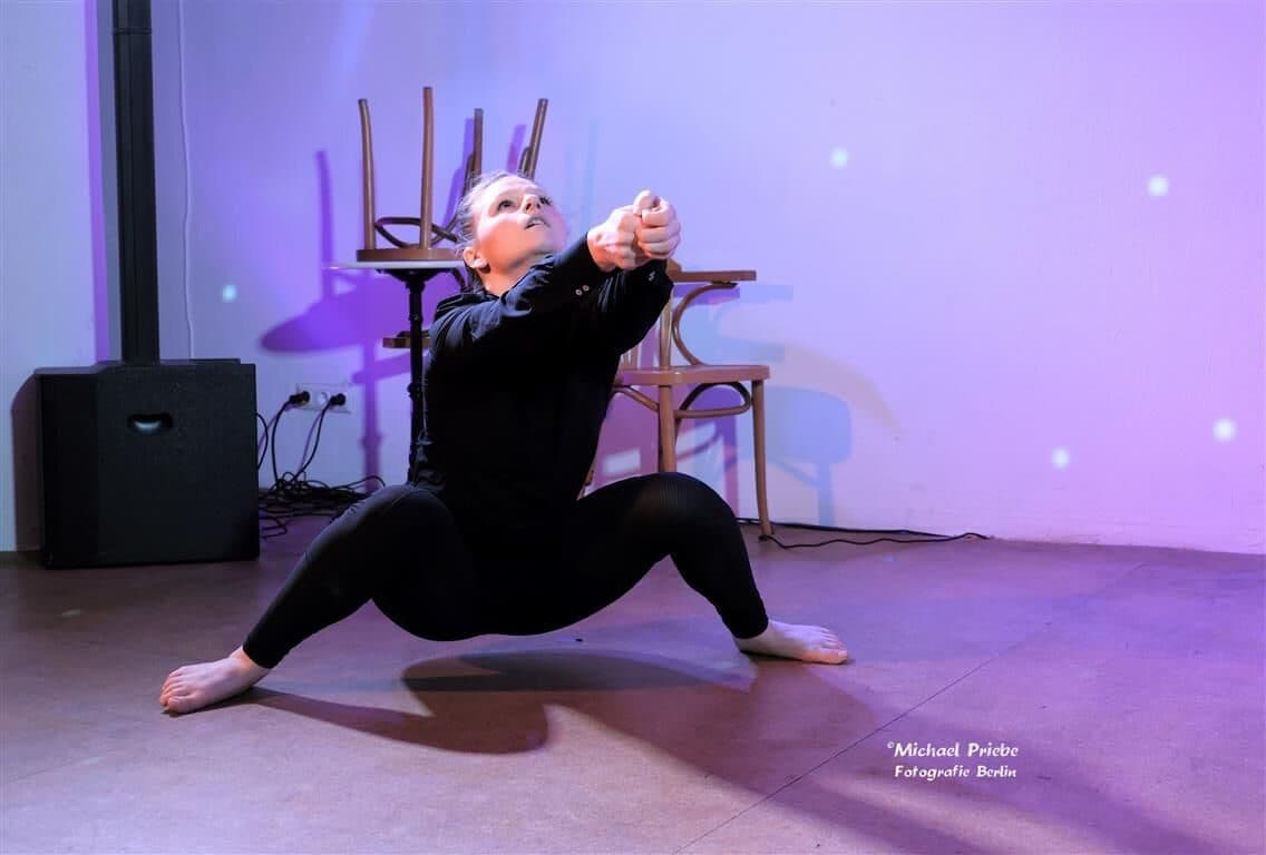 Laura in a deep lunge on a pink-lit stage