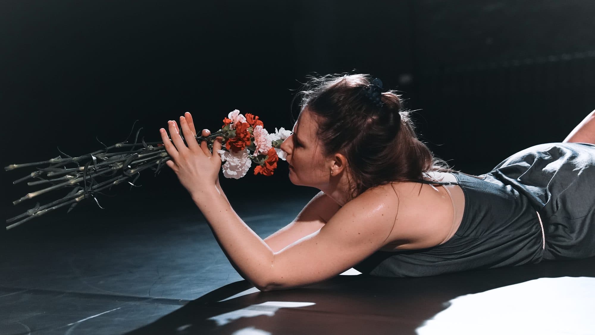 Laura lying on stage with a bouquet of flowers