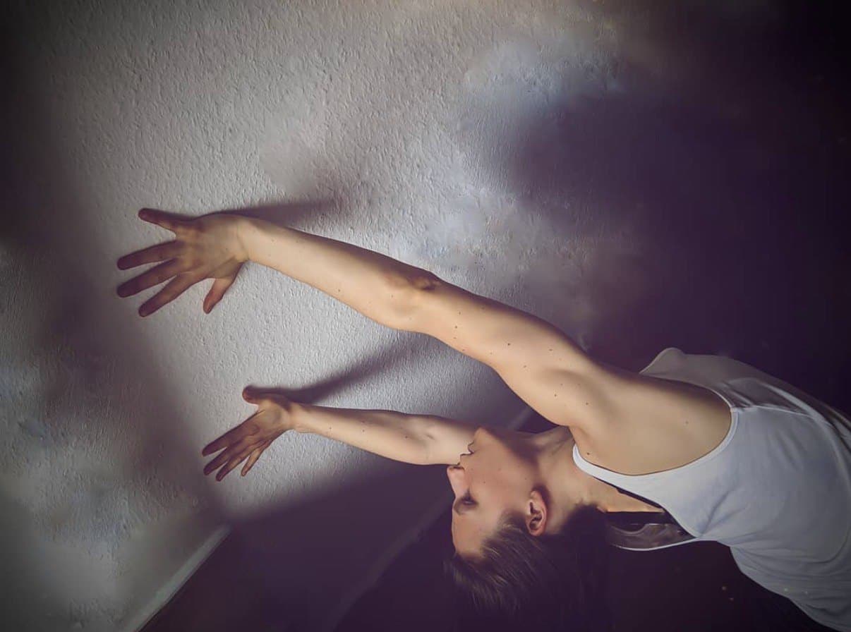 Laura upside down, arms stretched along a wall