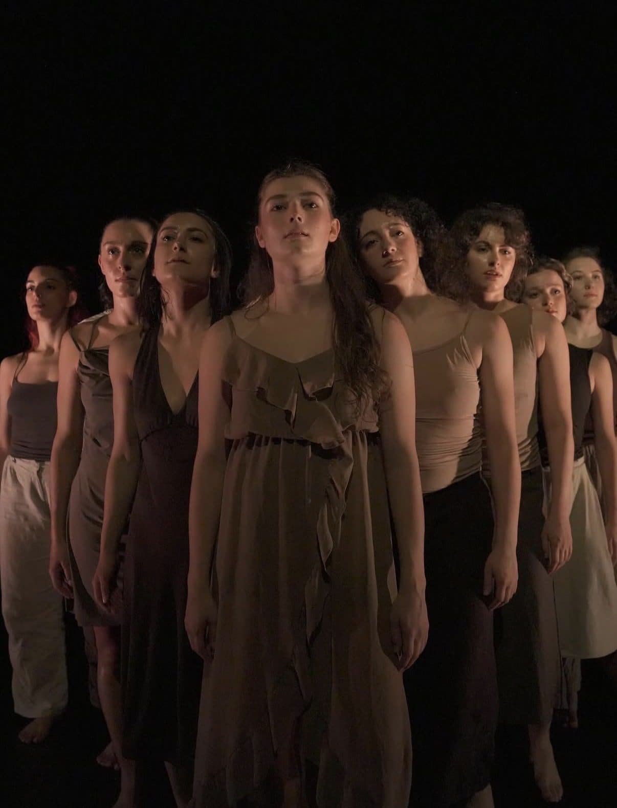 The ensemble standing close together in warm light
