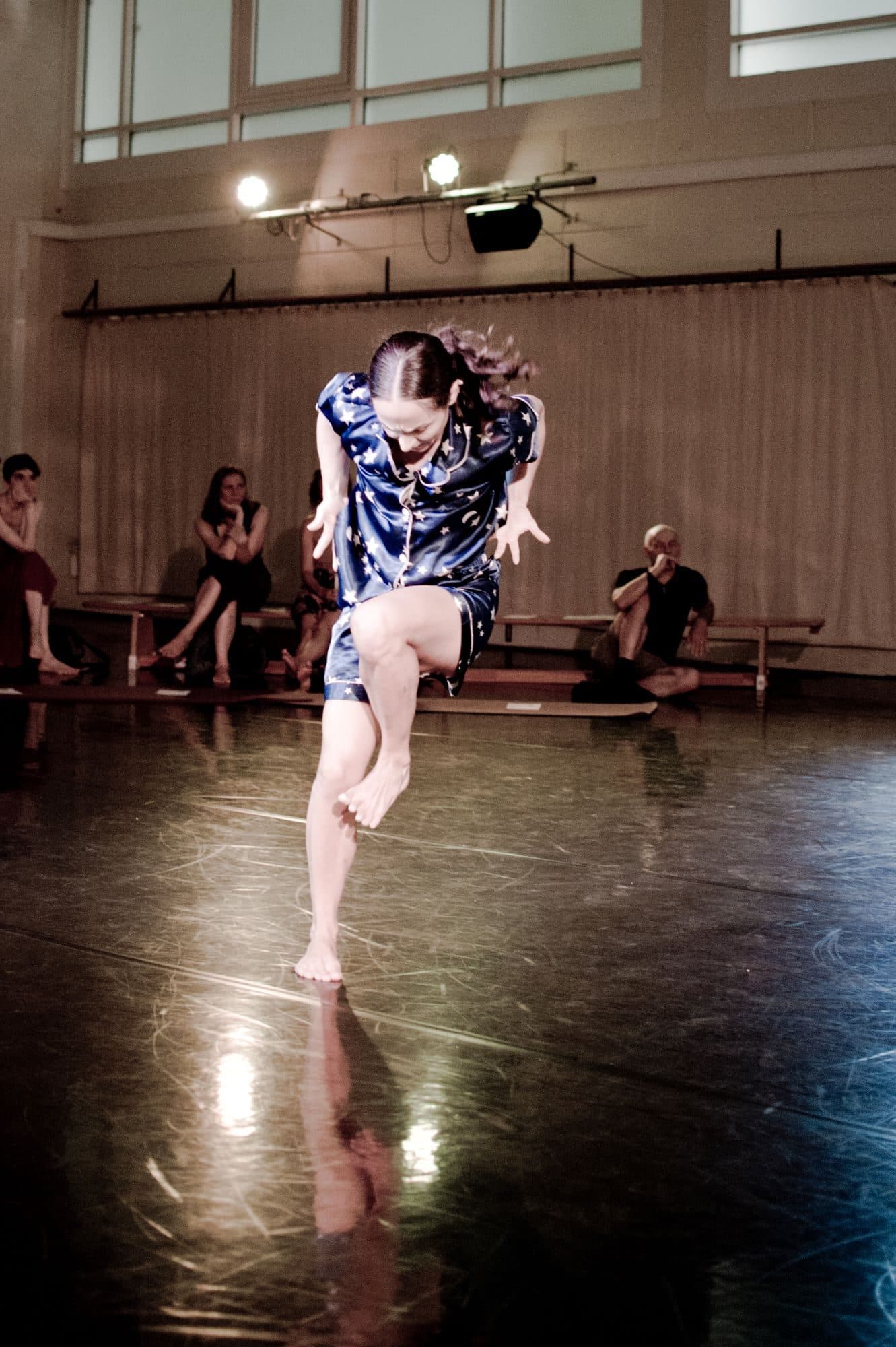 A dancer in pyjamas mid-leap in a studio